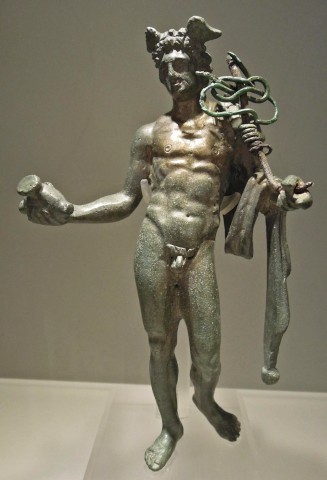 A bronze figurine of a fully nude, contrapposto Mercury with large wings in His hair and the chlamys draped over His left arm. He holds a money bag in His right hand and the caduceus against his shoulder in His left. The caduceus is a short rod that's been swallowed up in the mangled remains of wire that still somewhat show the loops and knots of the snakes.