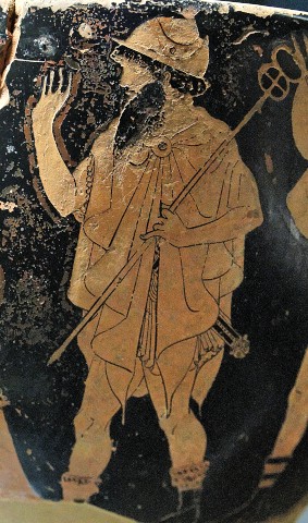 Closeup of a damaged white-figure vase showing the mortal herald Talthybios. He raises one hand and holds His caduceus in the other. He wears a pileus, beard, a chiton wrapped around like a shawl, and boots without wings.